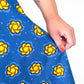 A close-up of a person's hand delicately holding the blue dress, emphasizing the fabric's texture and the beautiful yellow elements.