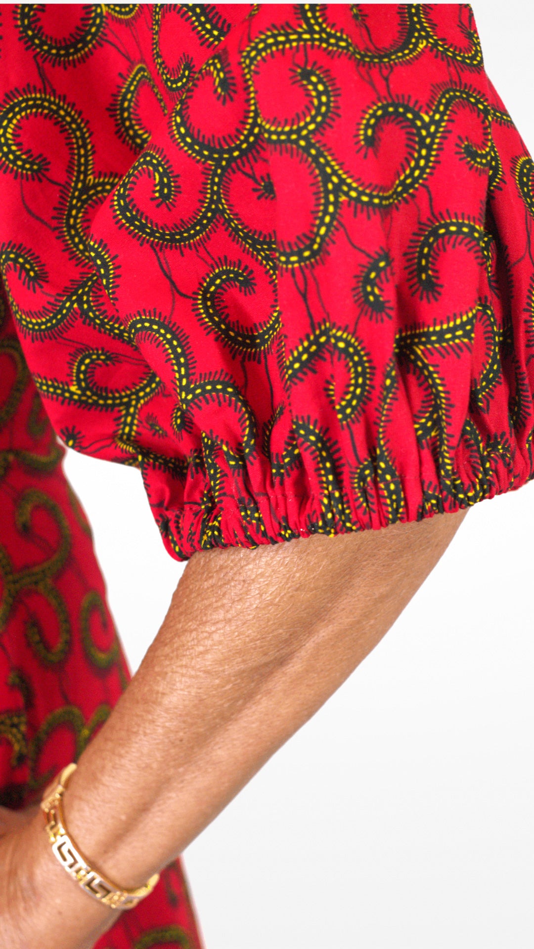 A close up of the puff sleeve of the red dress and its swirly details.