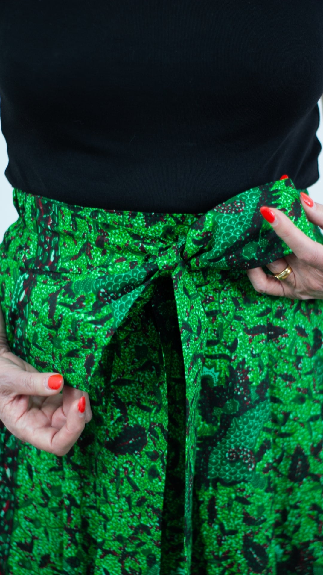 A close-up view capturing the details of a botanical green print skirt, featuring a tie belt tied in a trendy and cute bow.