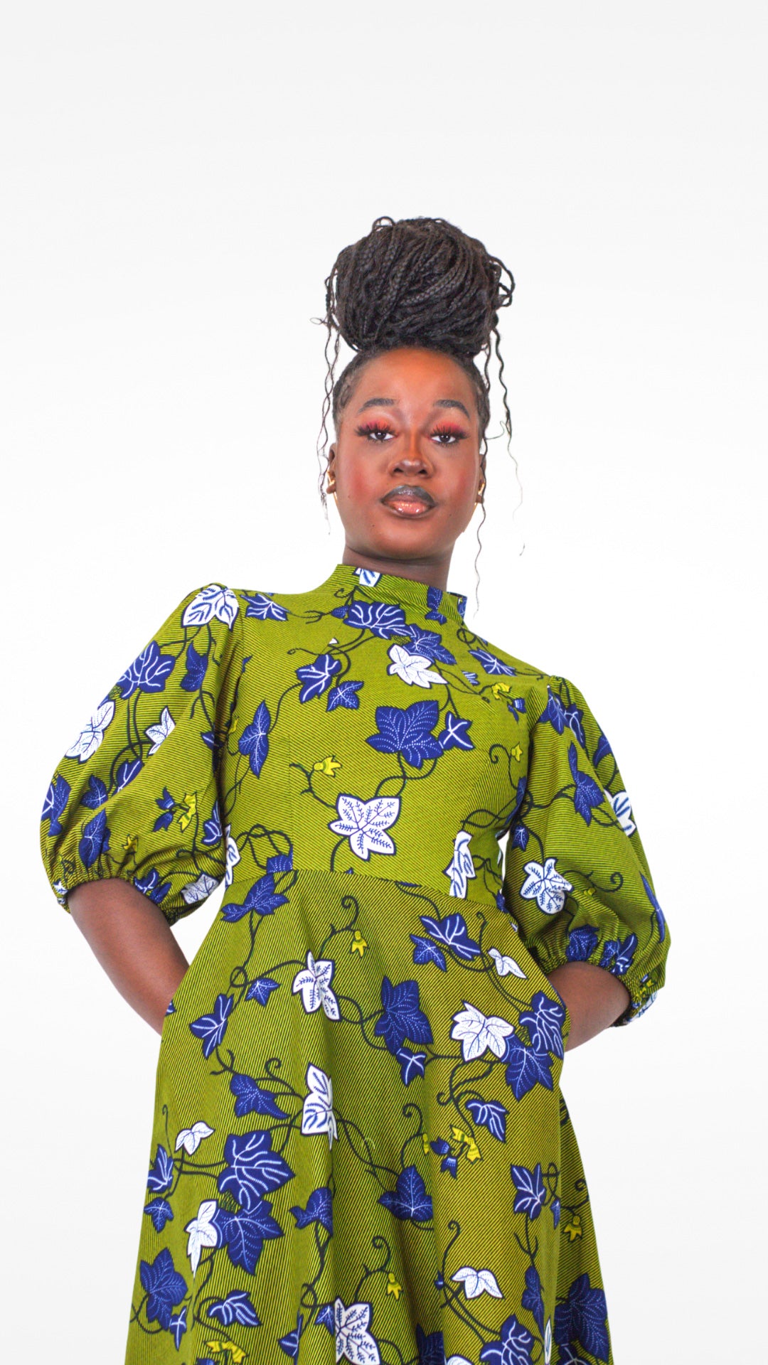 Model posing in khaki dress adorned with a blue and white leaves pattern.