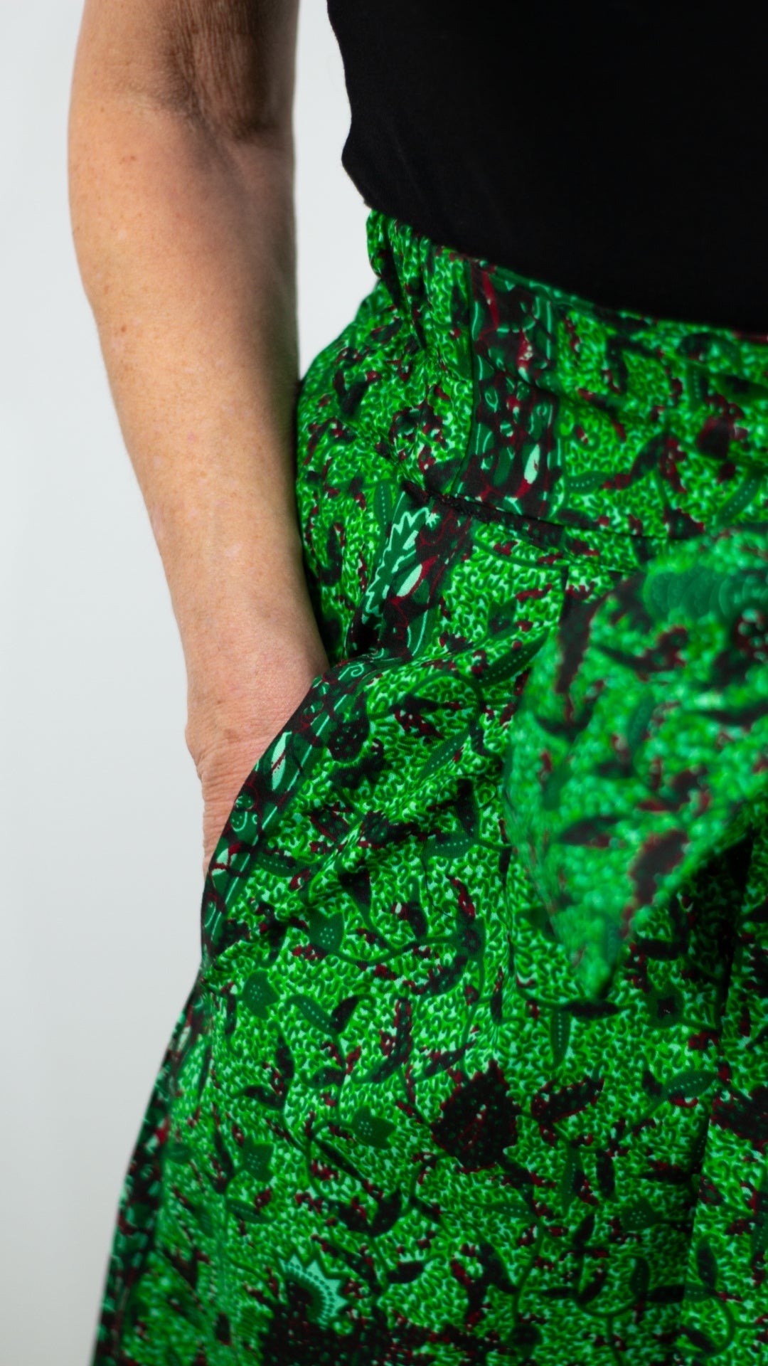 Close-up view highlighting the details of a botanical geen print skirt, showcasing the rich and vibrant patterns and deep pockets of the design.