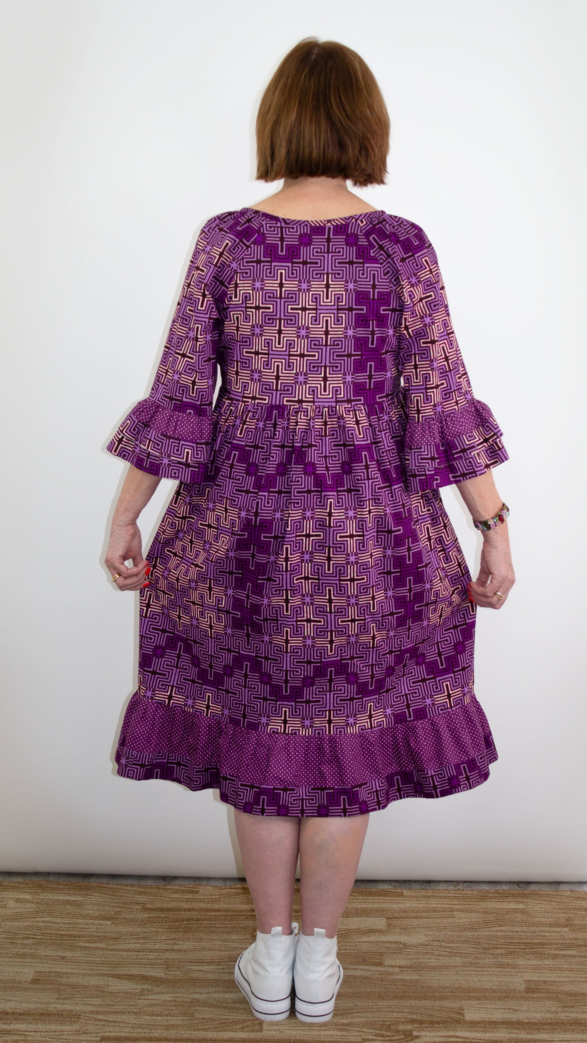 A back view capturing the elegance of a purple ruffle dress featuring a charming ruffle design at the bottom and elbow-length sleeves and playful designs.