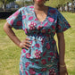 A woman wearing the blue print kaftan dress with pink elements in a park setting, posing confidently.