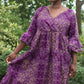 A woman exuding casual elegance while wearing the purple ruffle dress in a serene park setting.