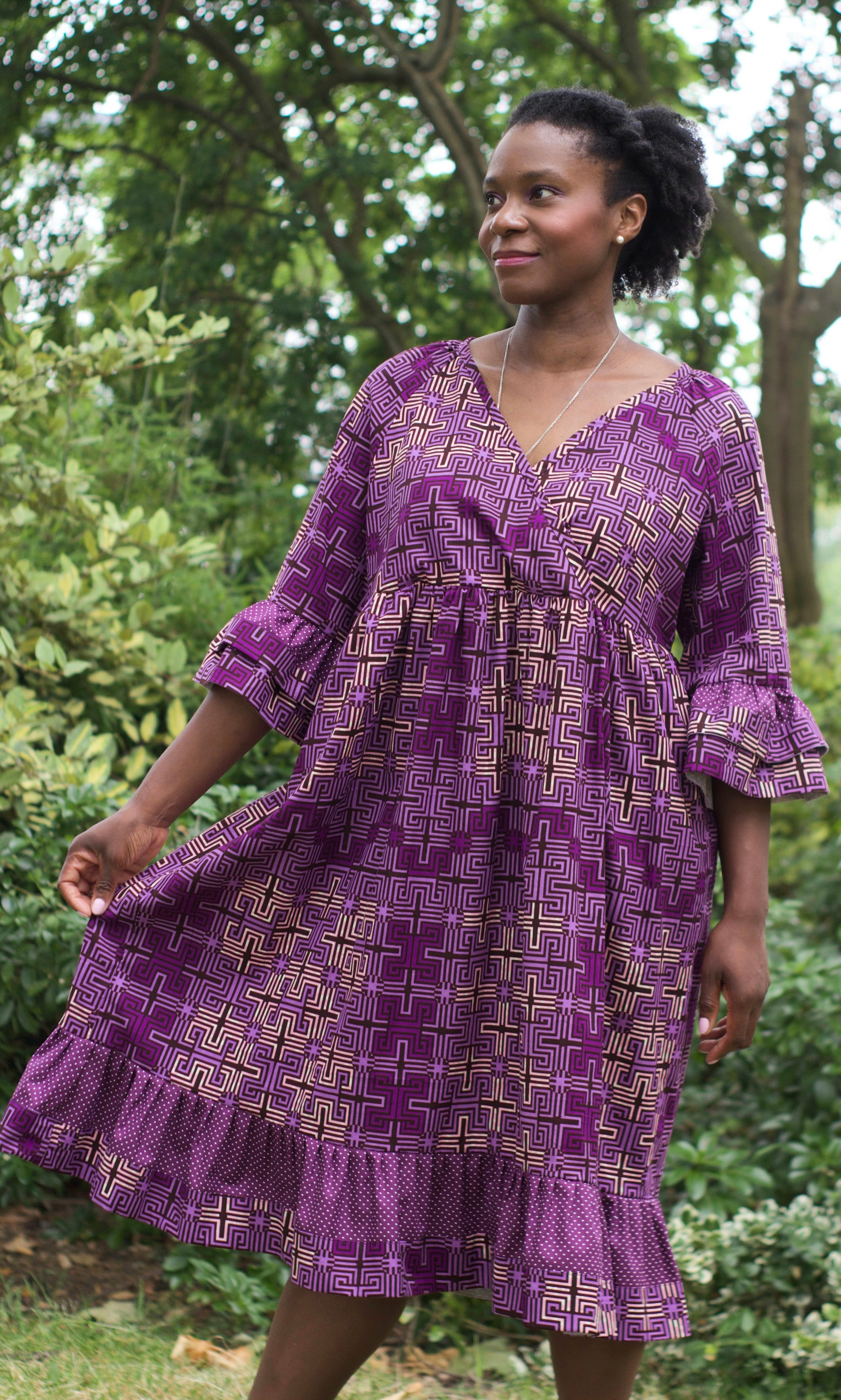 A woman exuding casual elegance while wearing the purple ruffle dress in a serene park setting.