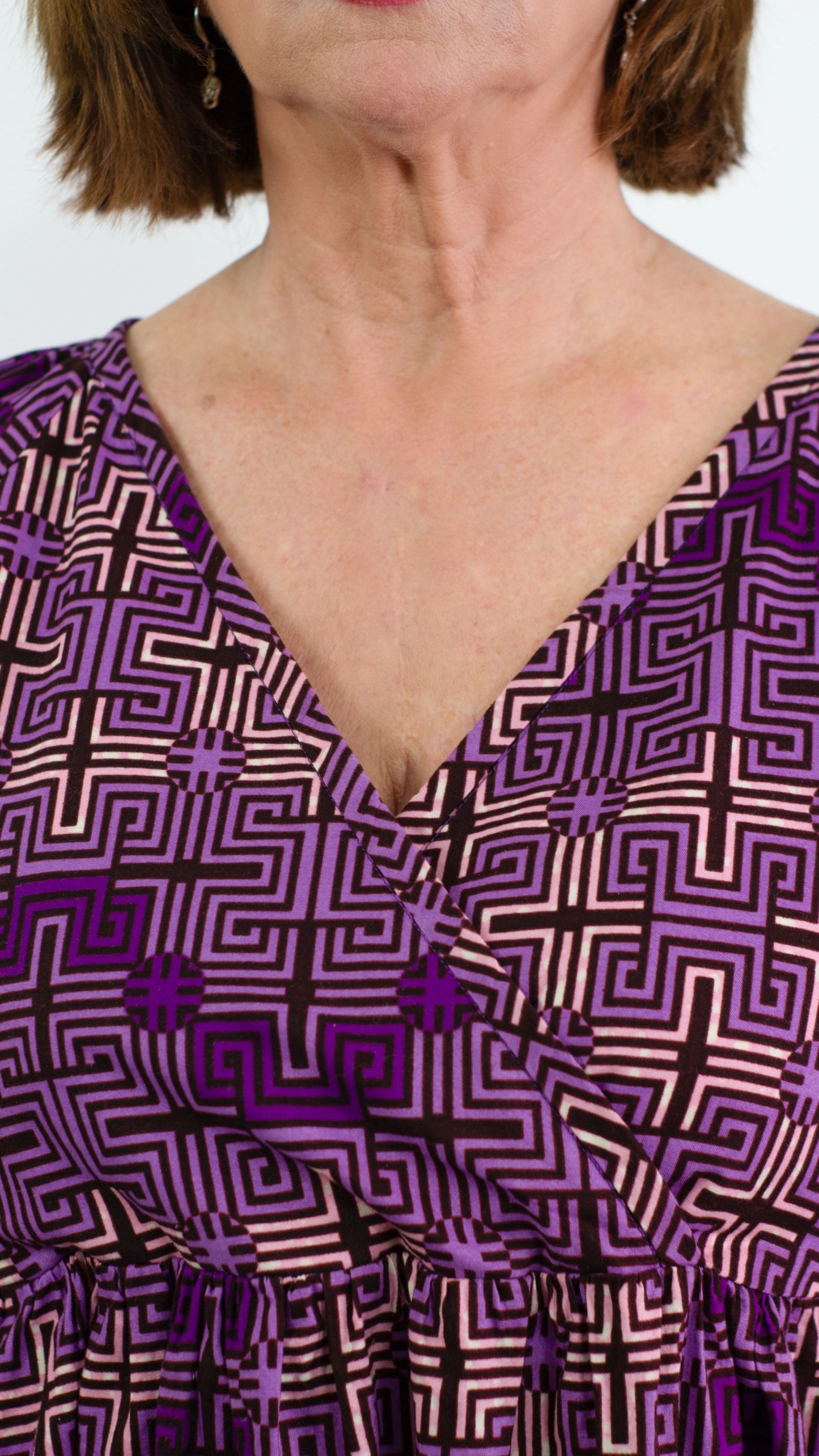 A close-up highlighting the neckline of the purple ruffle dress, showcasing the seamless blend of playful design elements and a feminine silhouette.