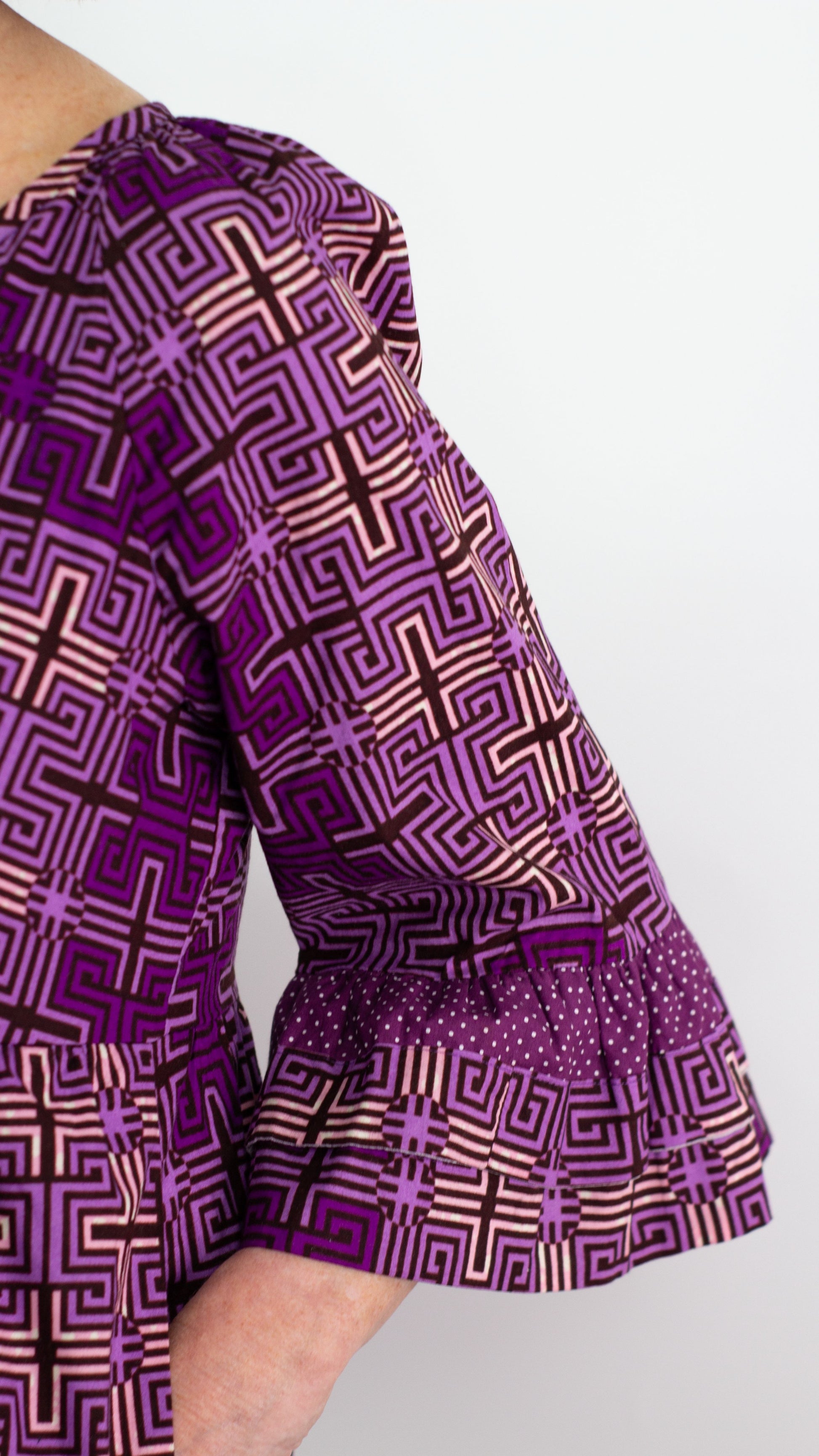 a close up view of the medium length purple ruffle sleeve, highlighting the playful designs of the print.