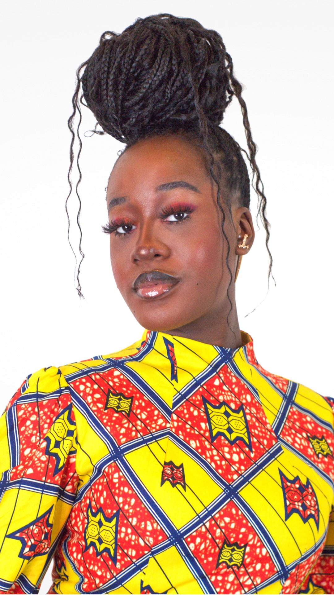 A close-up of the neckline of the dress, showcasing its elements, with model's makeup featuring red eyeshadow and black lip pencil.