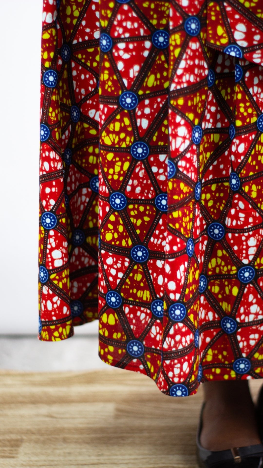 The lower section of a mosaic African print long skirt, elegantly paired with black ballet flats.