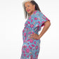 A model posing confidently in a blue kaftan dress with a pink floral print, showcasing the waistline of the dress.