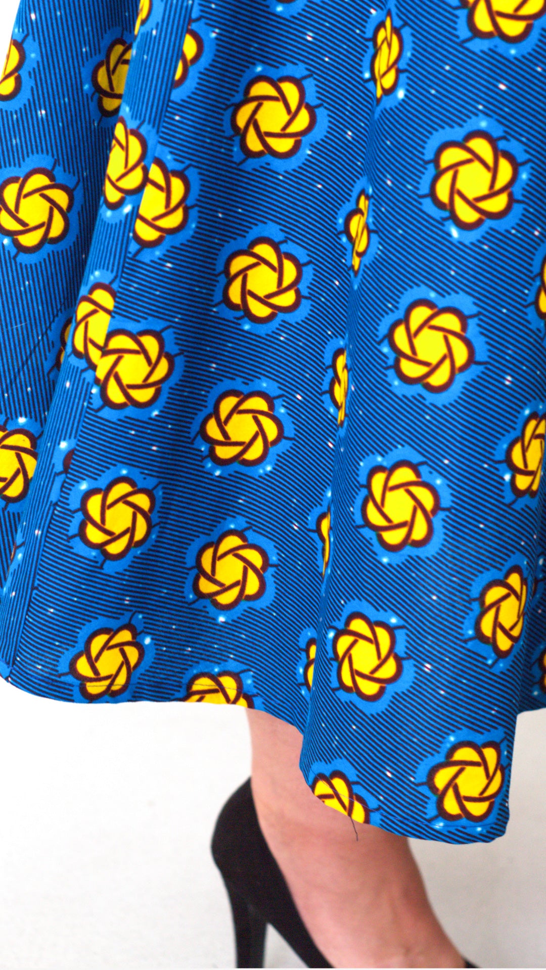 A close-up gracefully highlights the blue fabric and intricate yellow design details at the bottom of the dress.