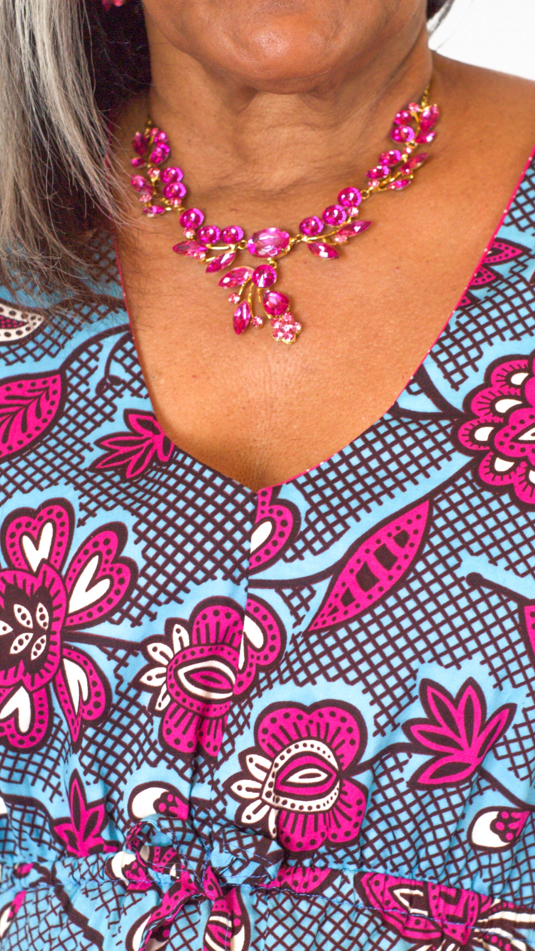 A close-up view focusing on the neckline of the blue print kaftan-style dress with pink elements. 