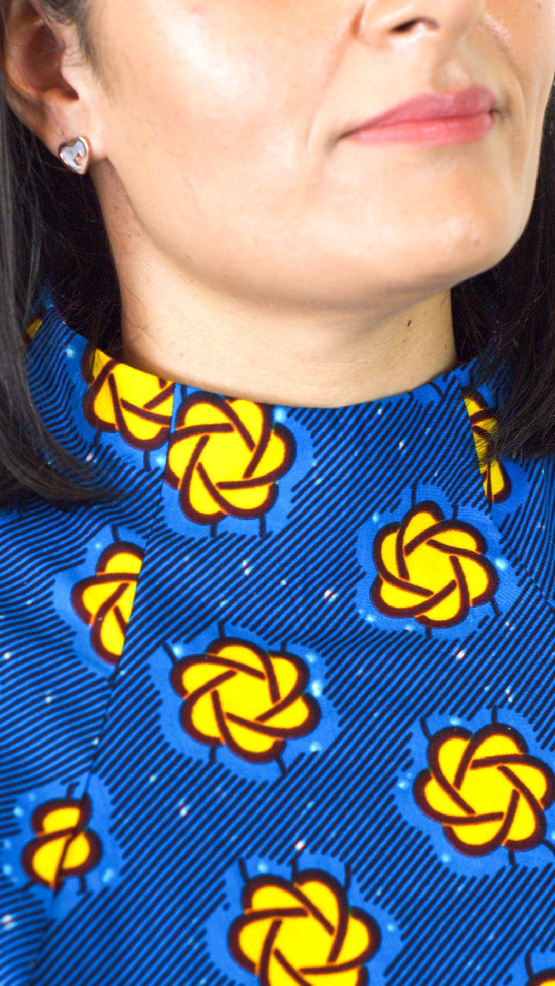 A close-up view captures the details of the neckline of the blue dress, adorned with yellow elements.