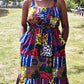 A woman exuding joy and style, gracefully posing with a radiant smile in a maxi long print patchwork dress paired with elegant jewellery in a park setting. 