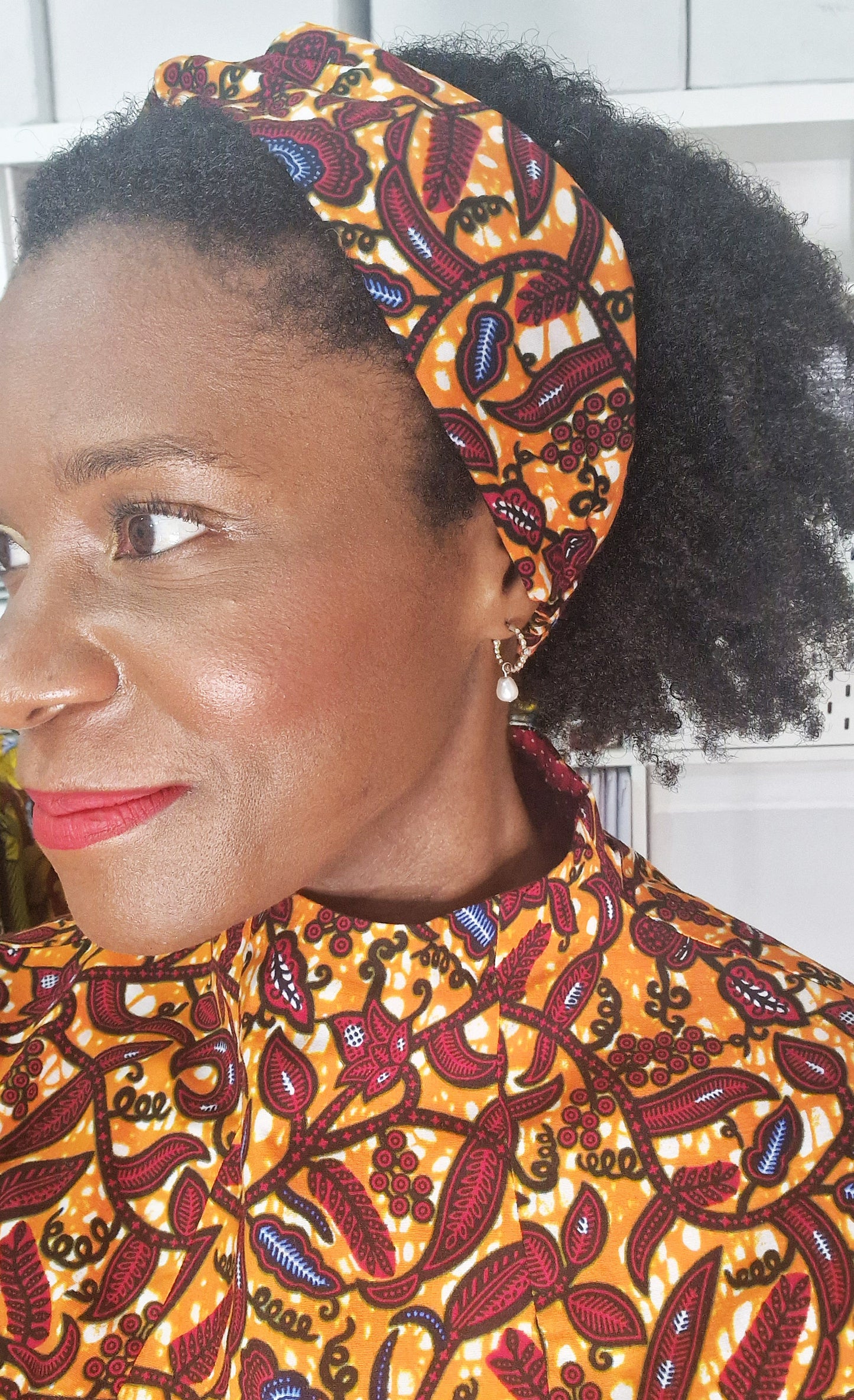 A woman wearing the orange patterned headband in a matching dress.