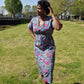 A woman strikes a pose in a stylish blue kaftan dress adorned with a pink floral print in a park.. 