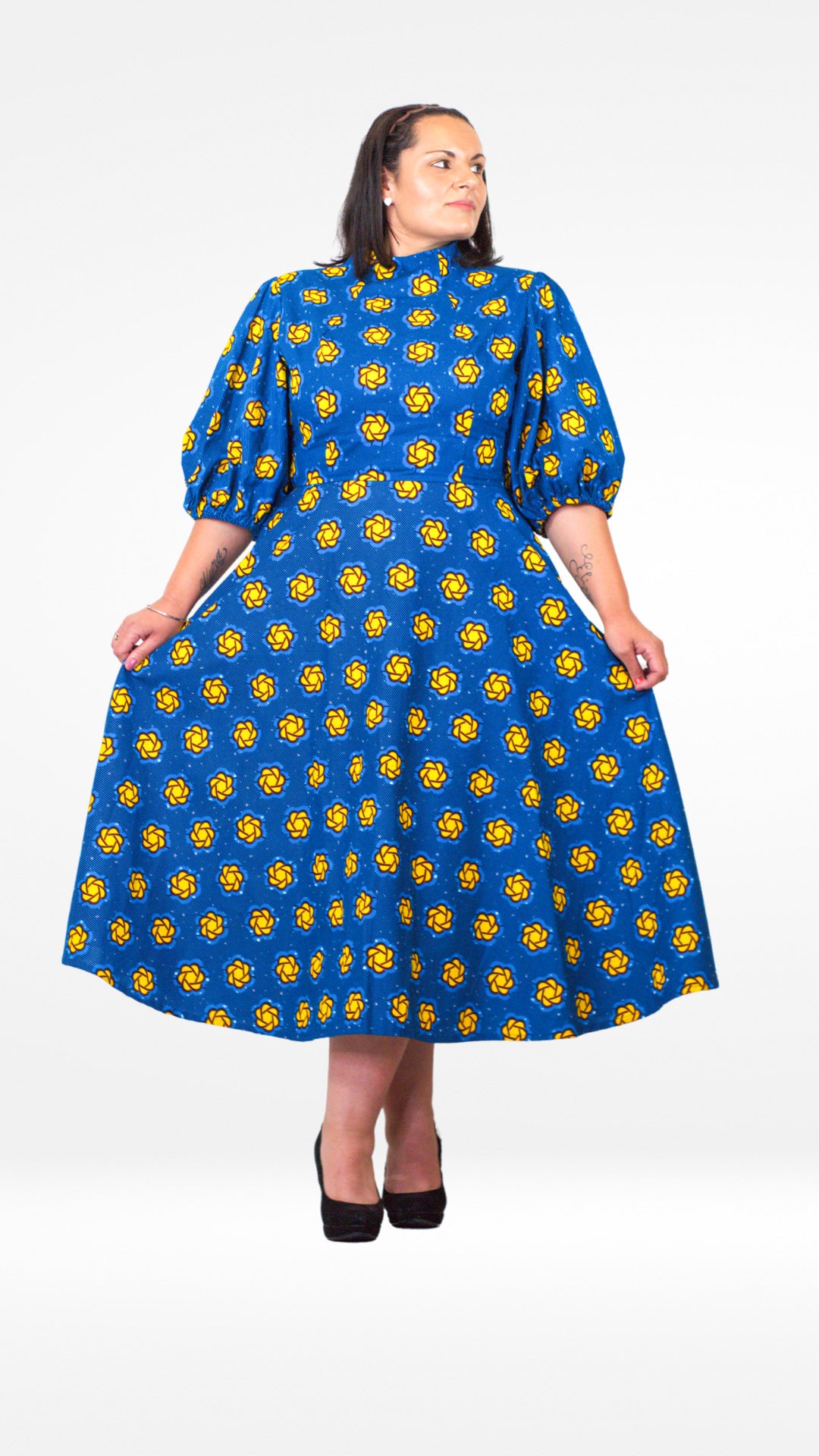 A model showcases a blue puff sleeve long dress adorned with playful yellow elements and paired with black classic heels.