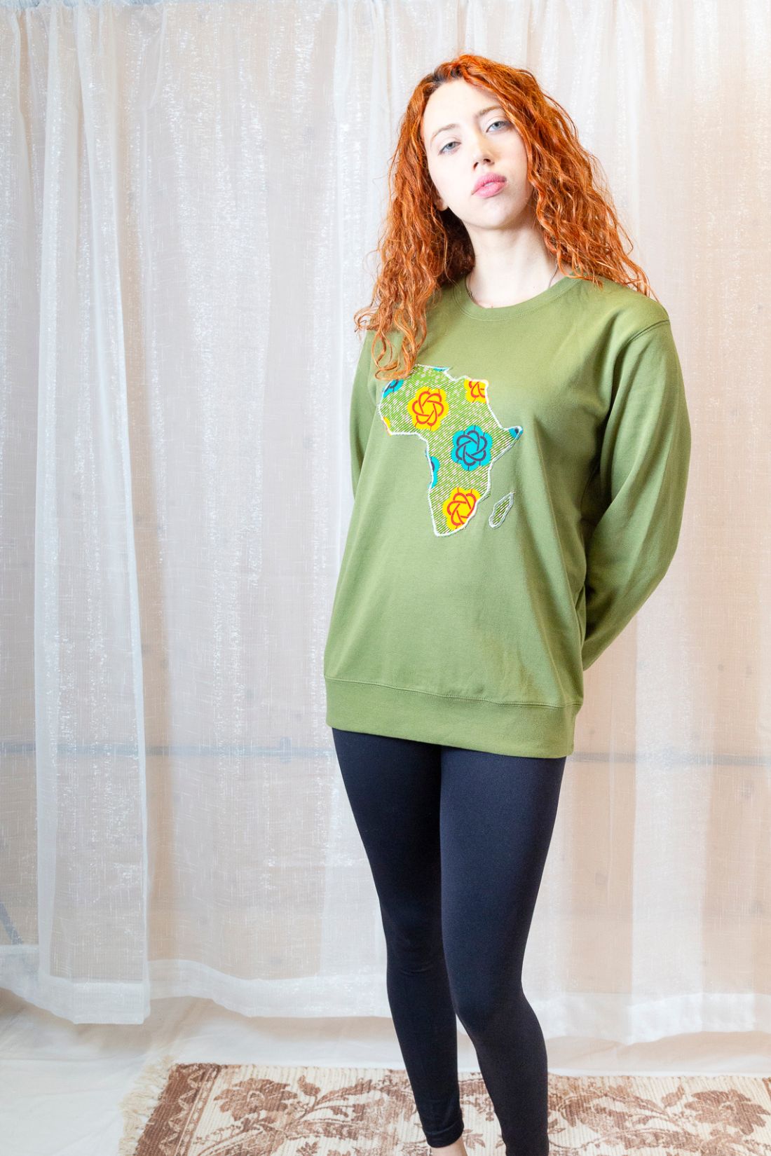 A person wearing a green sweatshirt with a map of Africa on it