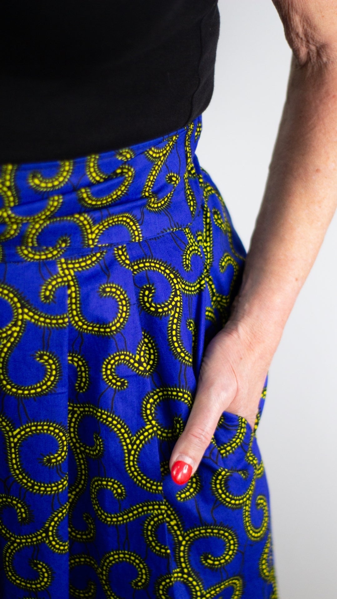 The pocket of a swirly blue print skirt with golden elements.
