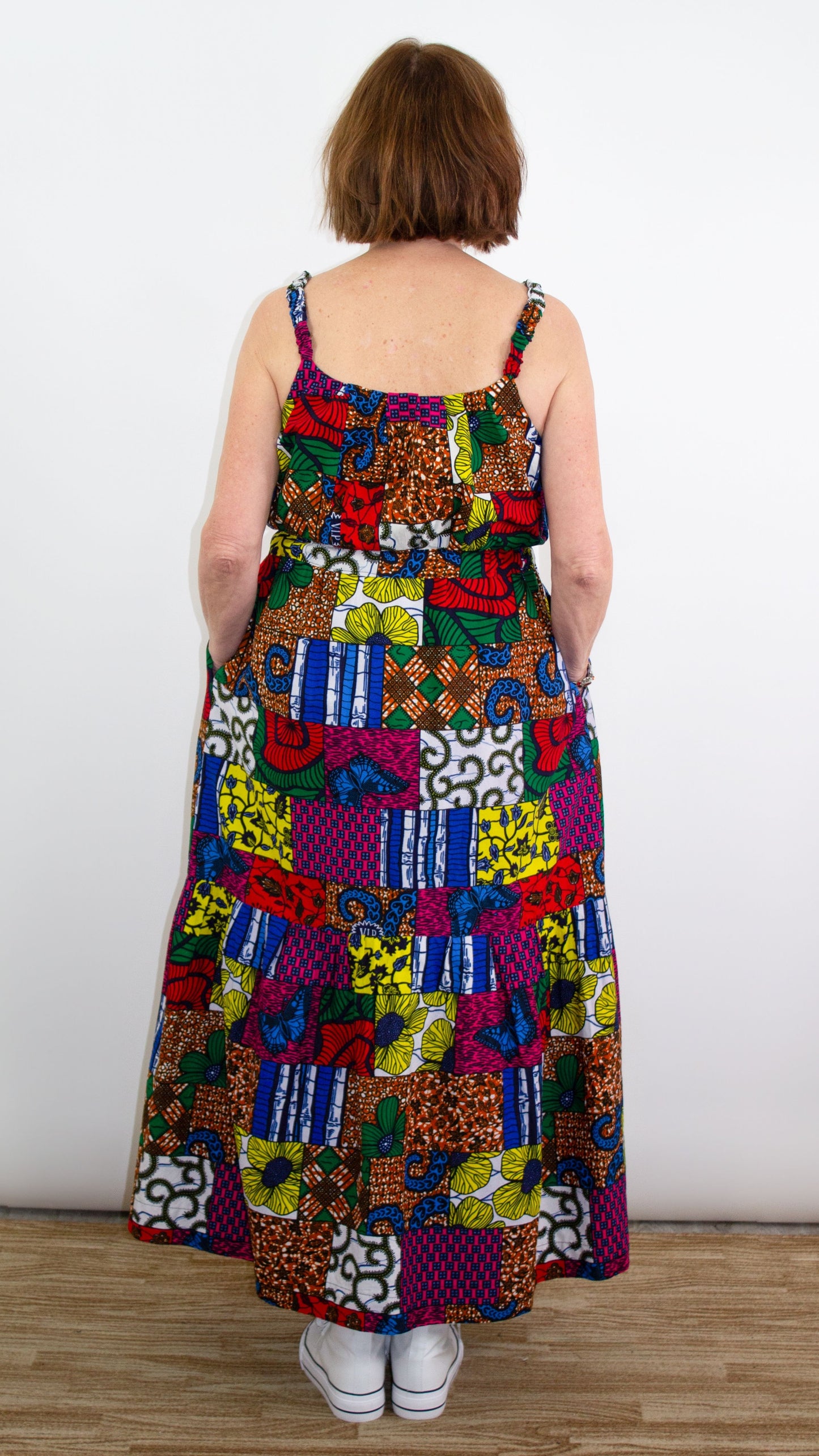 Back of a model striking a pose in a long maxi patchwork dress, showcasing the delicate straps