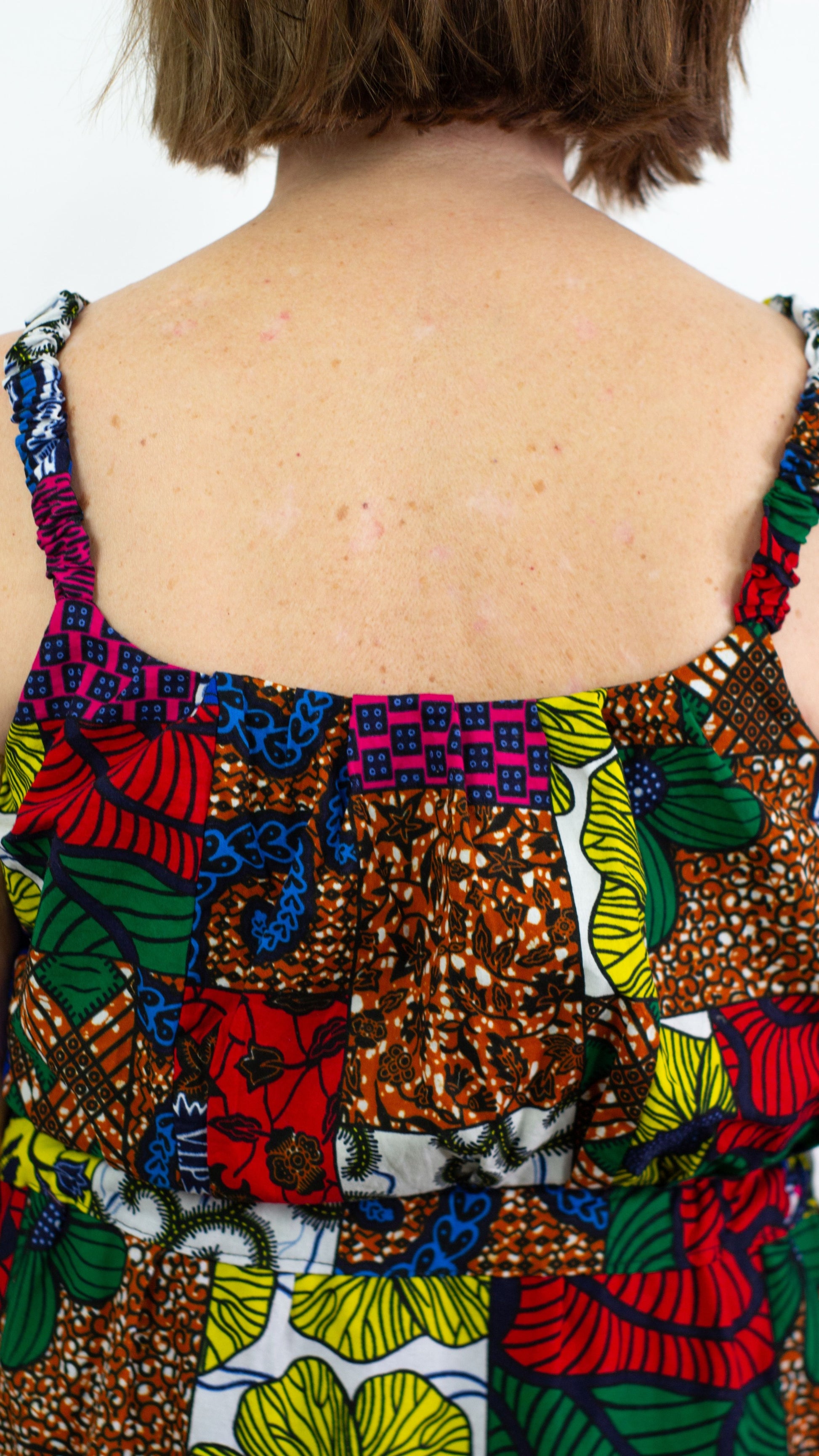 A close-up of the upper back portion of the dress, highlighting the details such as the straps, waistline, and colourful patchwork elements. 