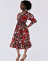 A woman confidently wears a red, black, and white floral African print Amaka Dress with a square neckline and ruffled sleeves.
Close-up of the smocked bodice, showcasing the vibrant floral pattern and elasticated detail.
Full view of the flared skirt, highlighting its volume, symmetrical pattern, and ruffled hem.