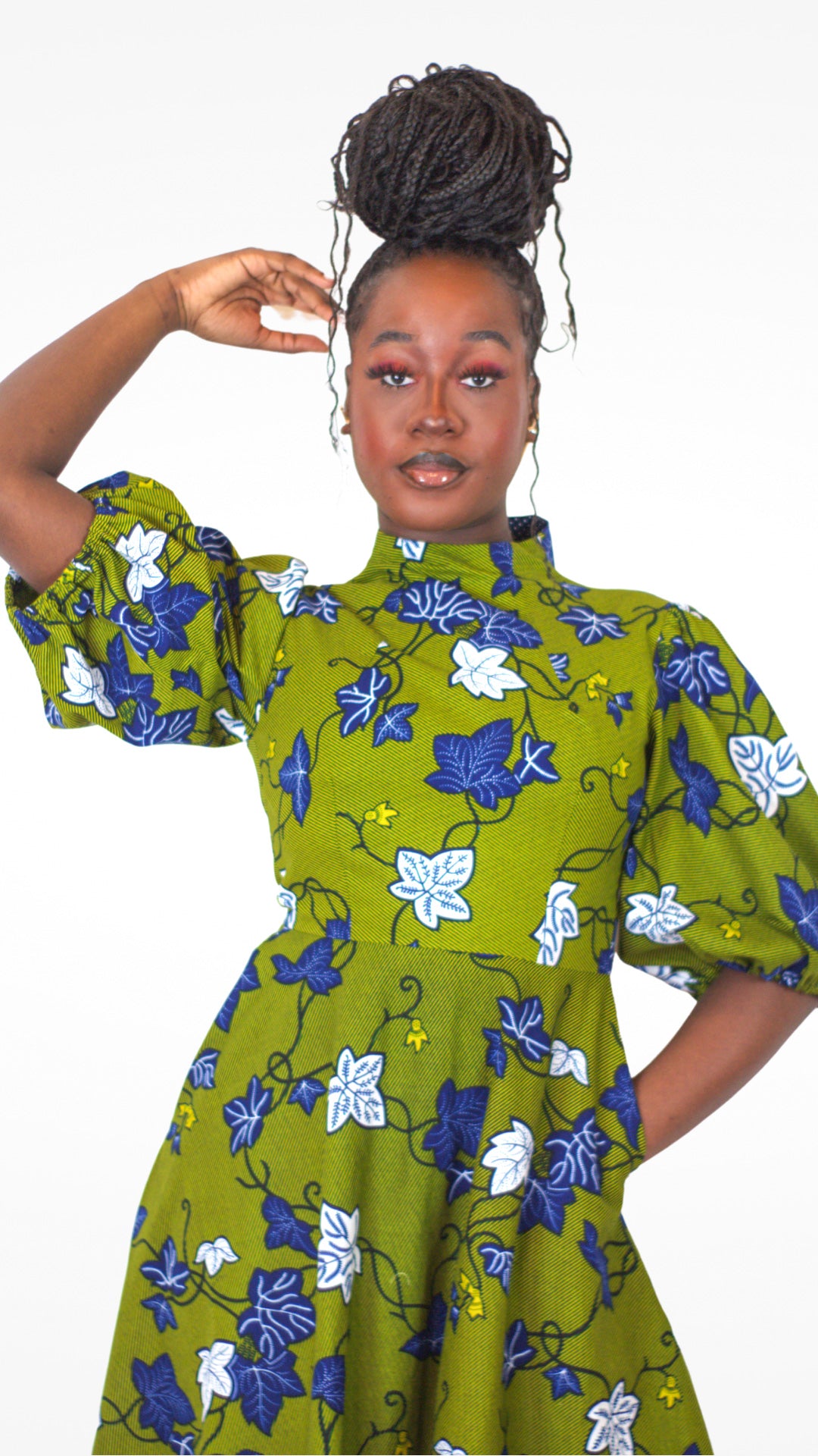 Model posing in a khaki dress adorned with a striking blue and white leaves pattern. 