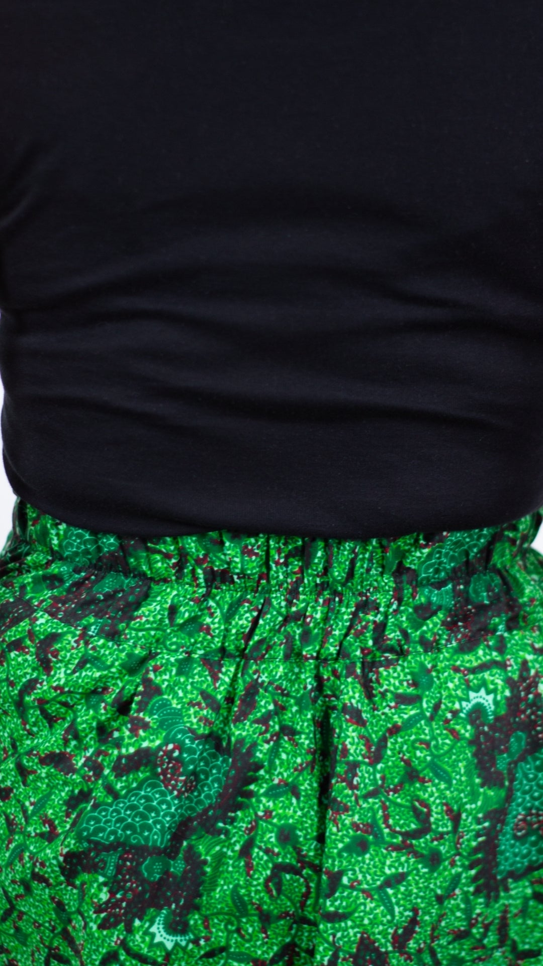 Close-up view highlighting the elasticised waistline of a botanical green print skirt.