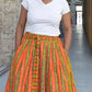 A joyful moment is captured as a woman smiles while wearing an orange-yellow striped skirt paired with a white top. 