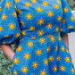 A close up of the yellow details, fitted waistline, high neck and puff sleeves of the blue print dress.