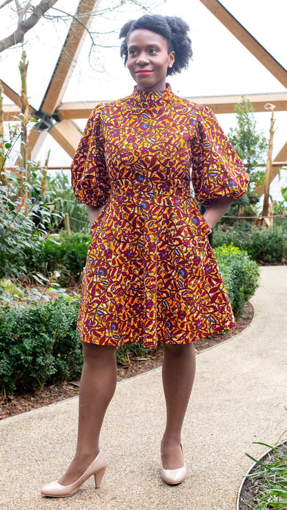 A person radiates happiness in an orange puff-sleeve dress, paired with beige heels.