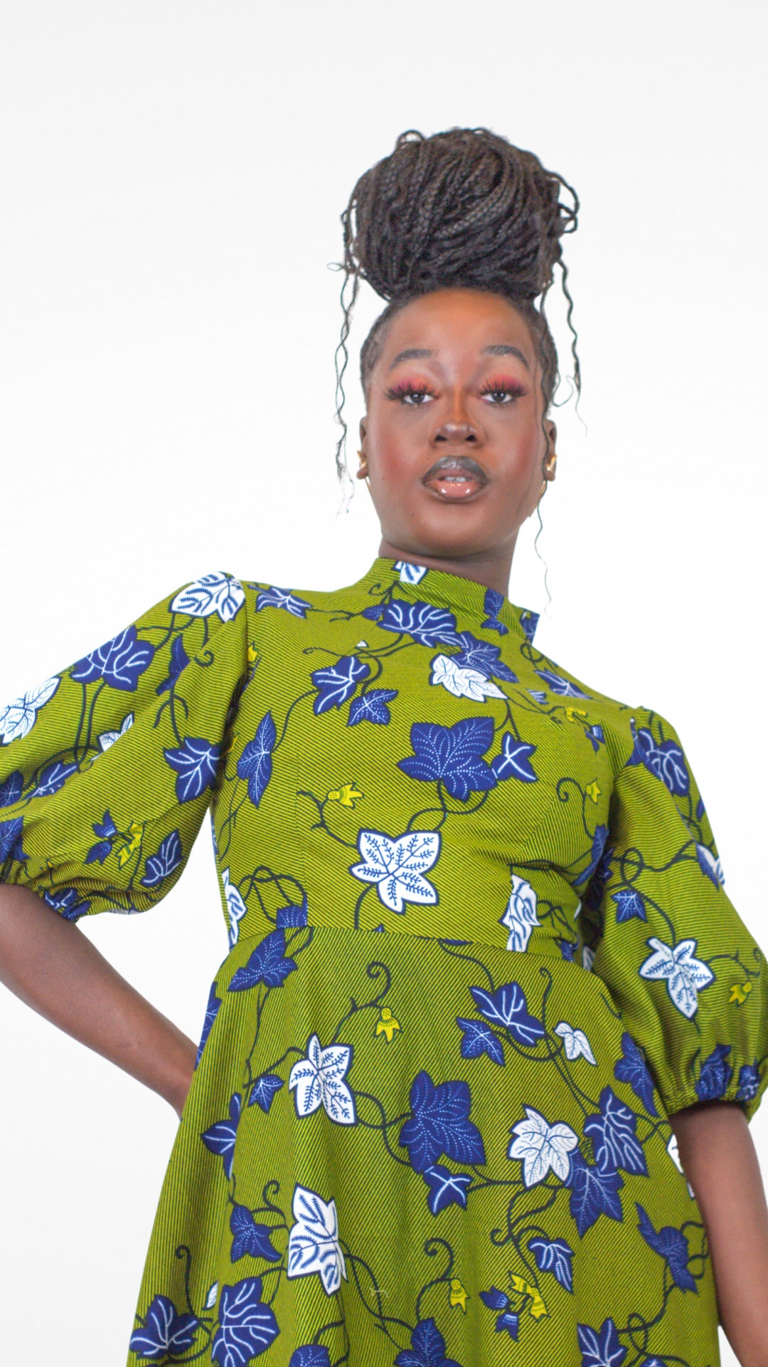 A woman poses in a khaki puff sleeve dress with a blue and white elements.