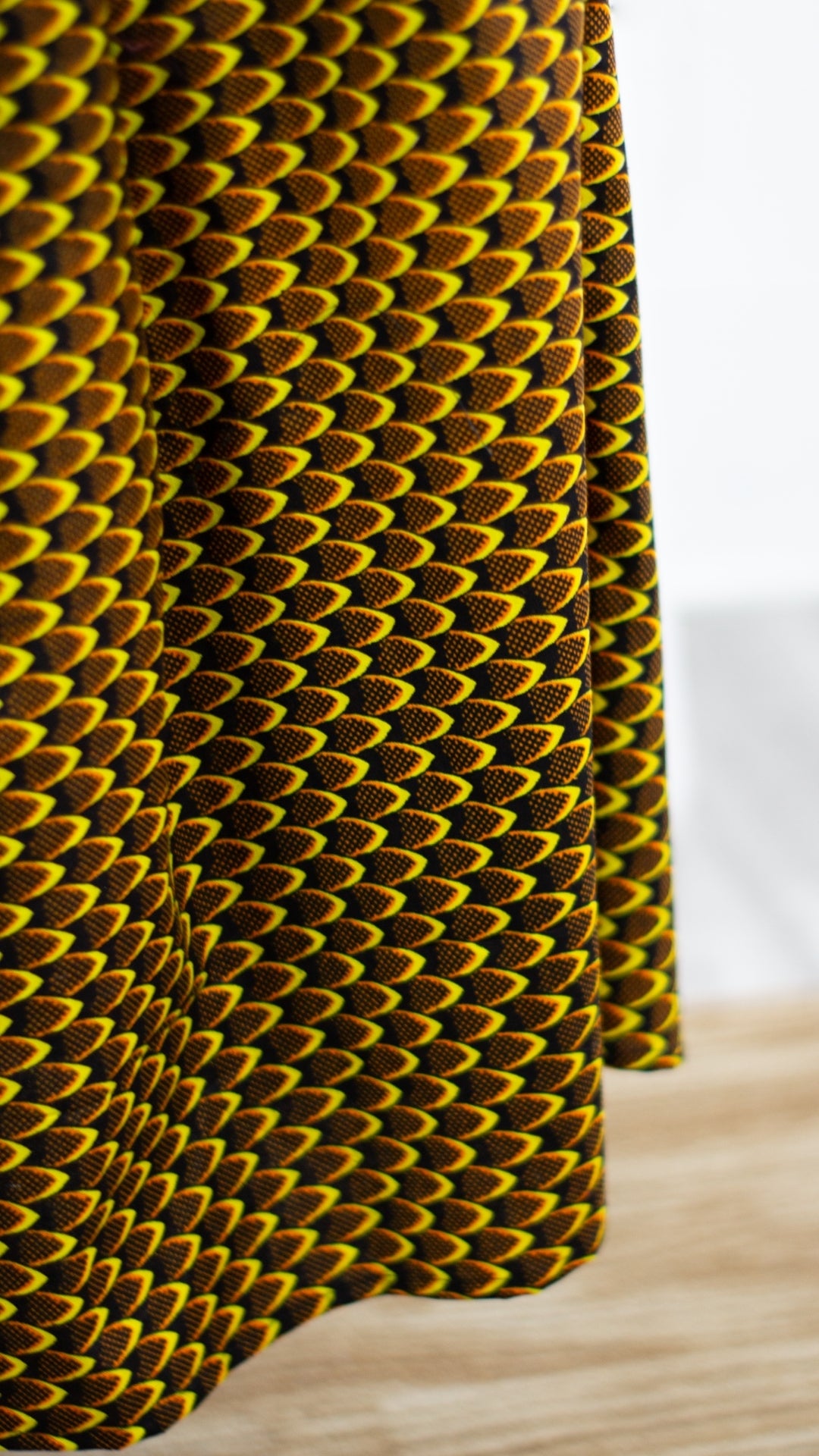 A close-up view highlighting the details of a yellow African print skirt, showcasing the vibrant patterns of the African print fabric.