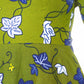 A close up of the waistline and detailed white and blue leafy elements of the khaki dress.