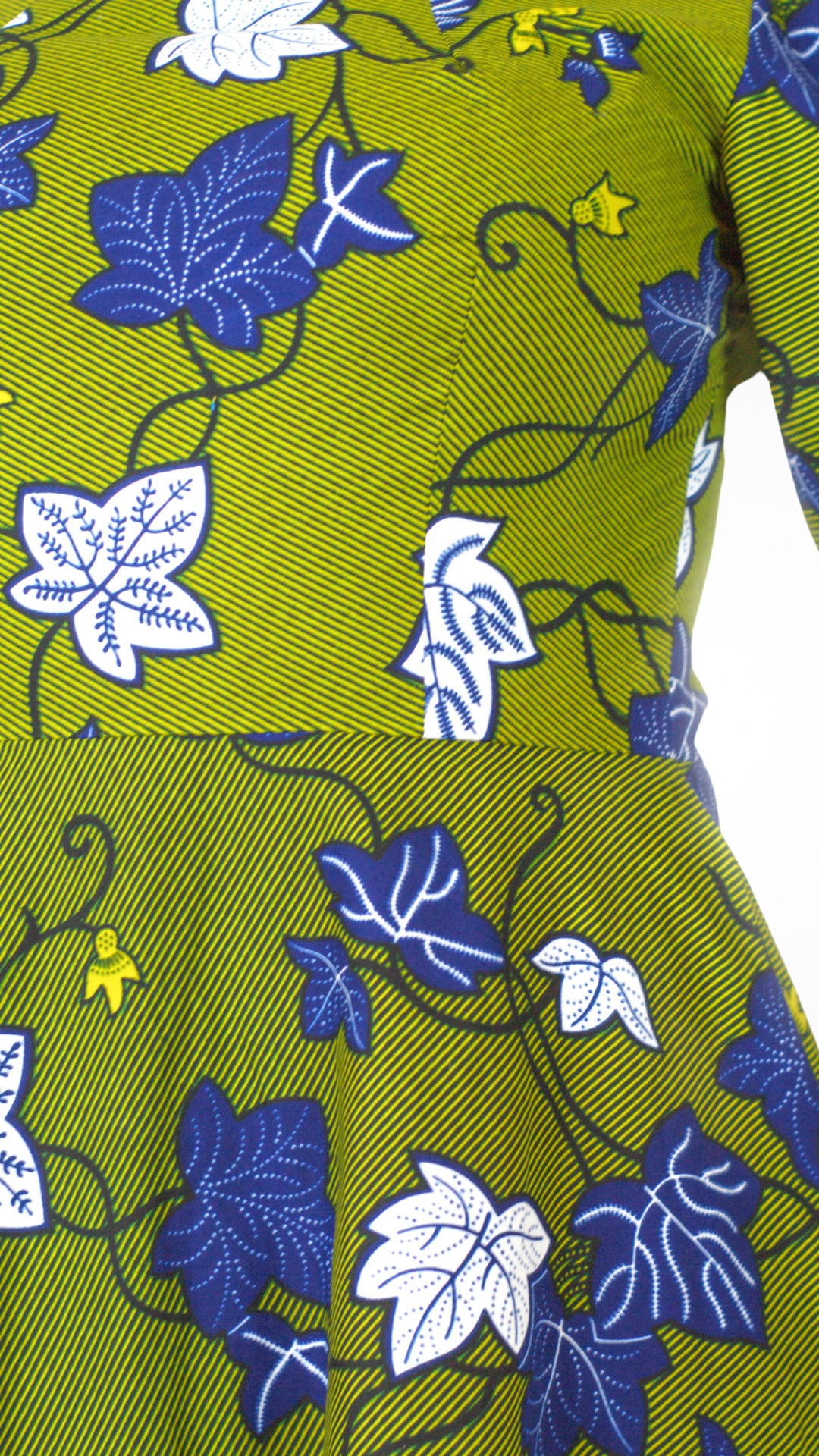 A close up of the waistline and detailed white and blue leafy elements of the khaki dress.