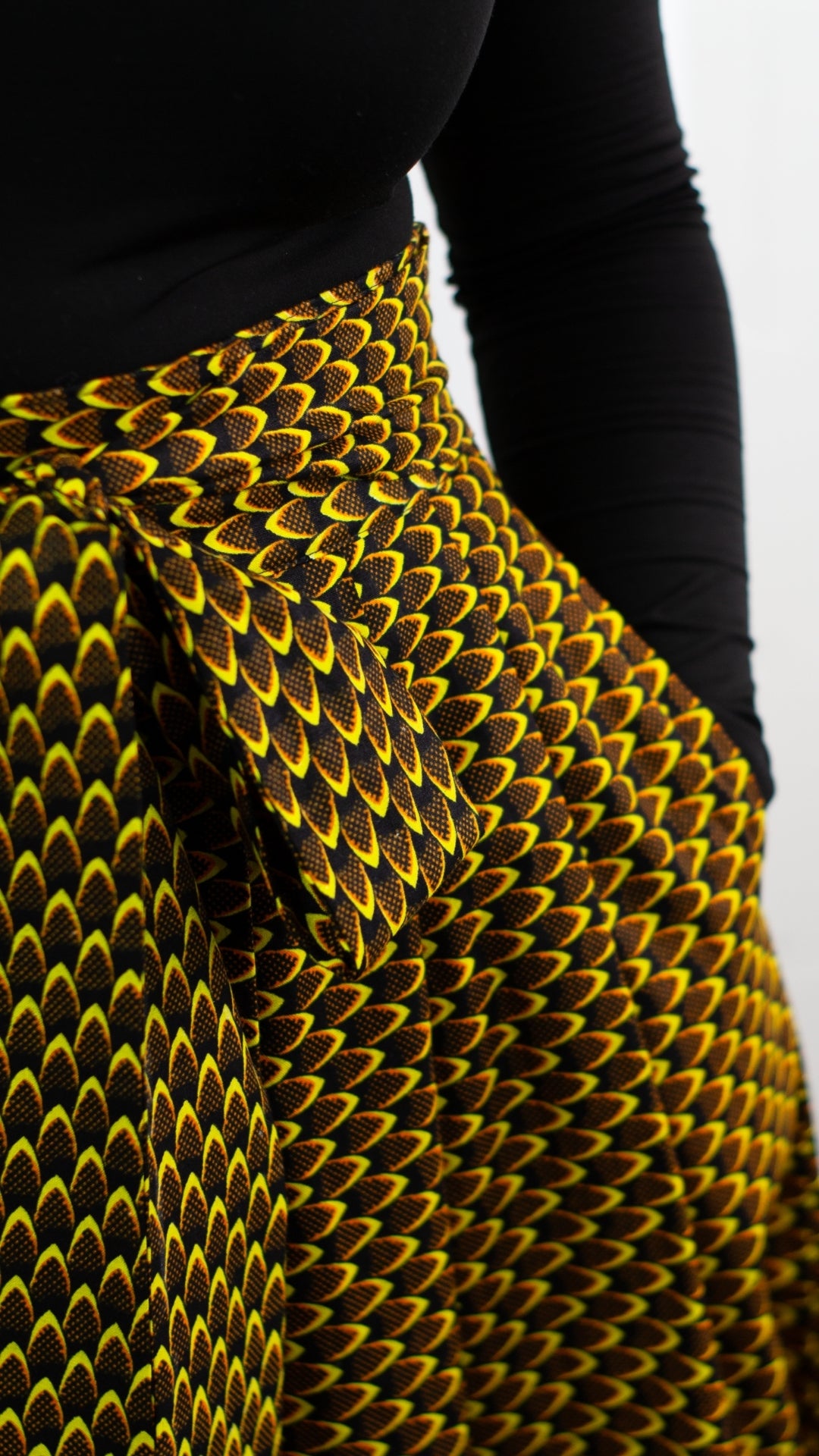 A close-up view capturing the intricate details of a pocket on a yellow-brown African print skirt. This image offers a detailed glimpse, showcasing the unique patterns and craftsmanship of the skirt in vivid detail.