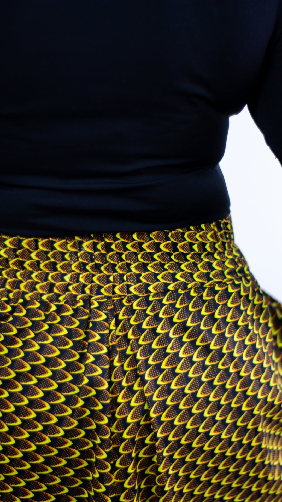 A  close-up highlighting the elasticised waist of a yellow African print skirt. This image provides a focused view of the elastic waistband, emphasizing the comfort and flexibility of the garment