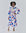 Alt Text: A woman poses in a white midi shirt dress adorned with a multicolored circular print. The dress features long puffed sleeves and a yellow piped button placket. One hand playfully holds the skirt.