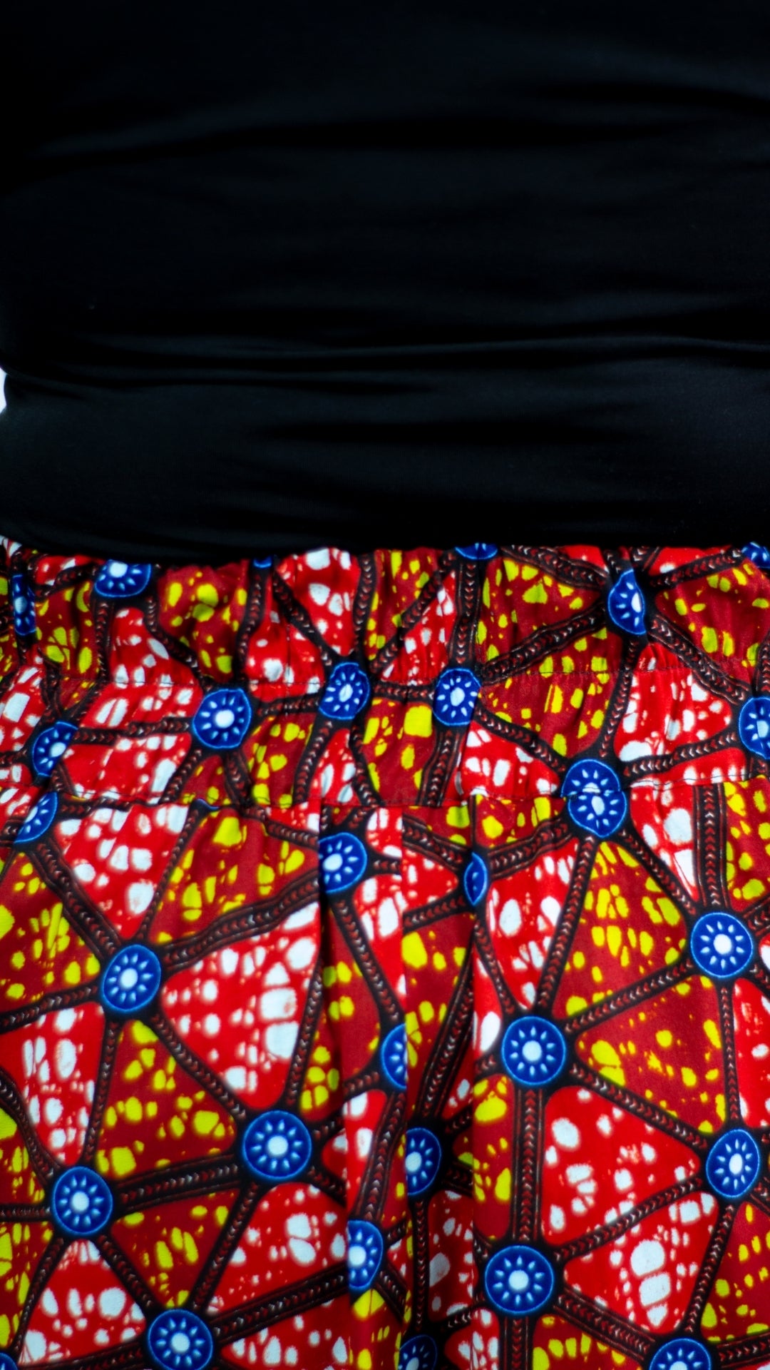 A detailed close-up of the waistline of a mosaic print long skirt.