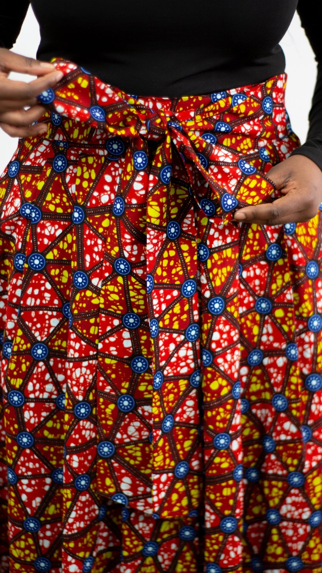 A detailed close-up of the fabric of a mosaic print long skirt, capturing tie belt skilfully tied into a trendy bow.