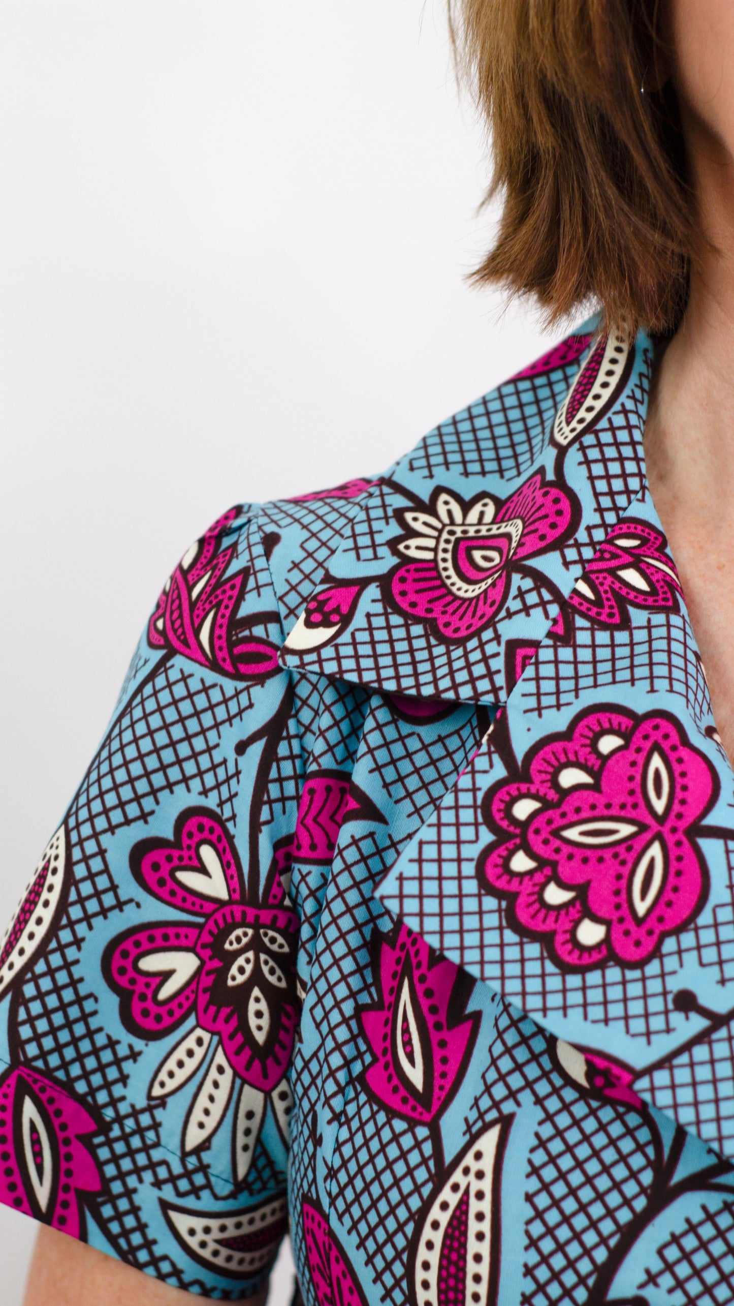 Close up of the beautiful print fabric of the blue dress, showcasing captivating pink floral motifs.