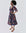 Woman wearing the Amaka Dress, showcasing its vibrant multi-colored smocked bodice and flared midi skirt.