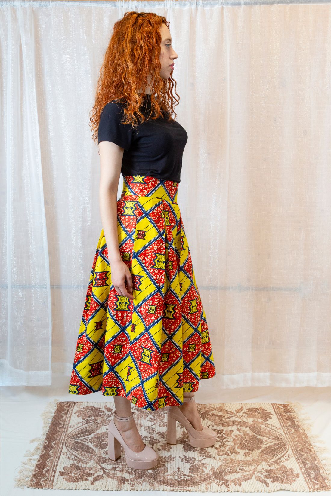 A person wearing an African print yellow and orange skirt