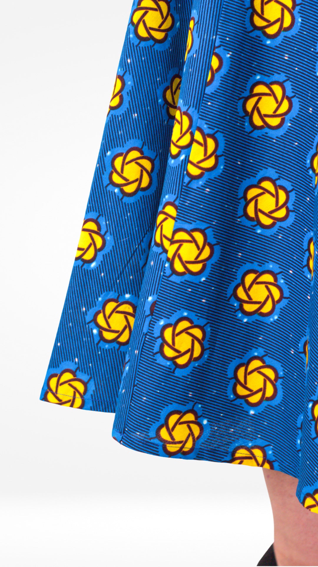A close-up, highlighting the blue fabric and yellow design details of the bottom of the dress gracefully.