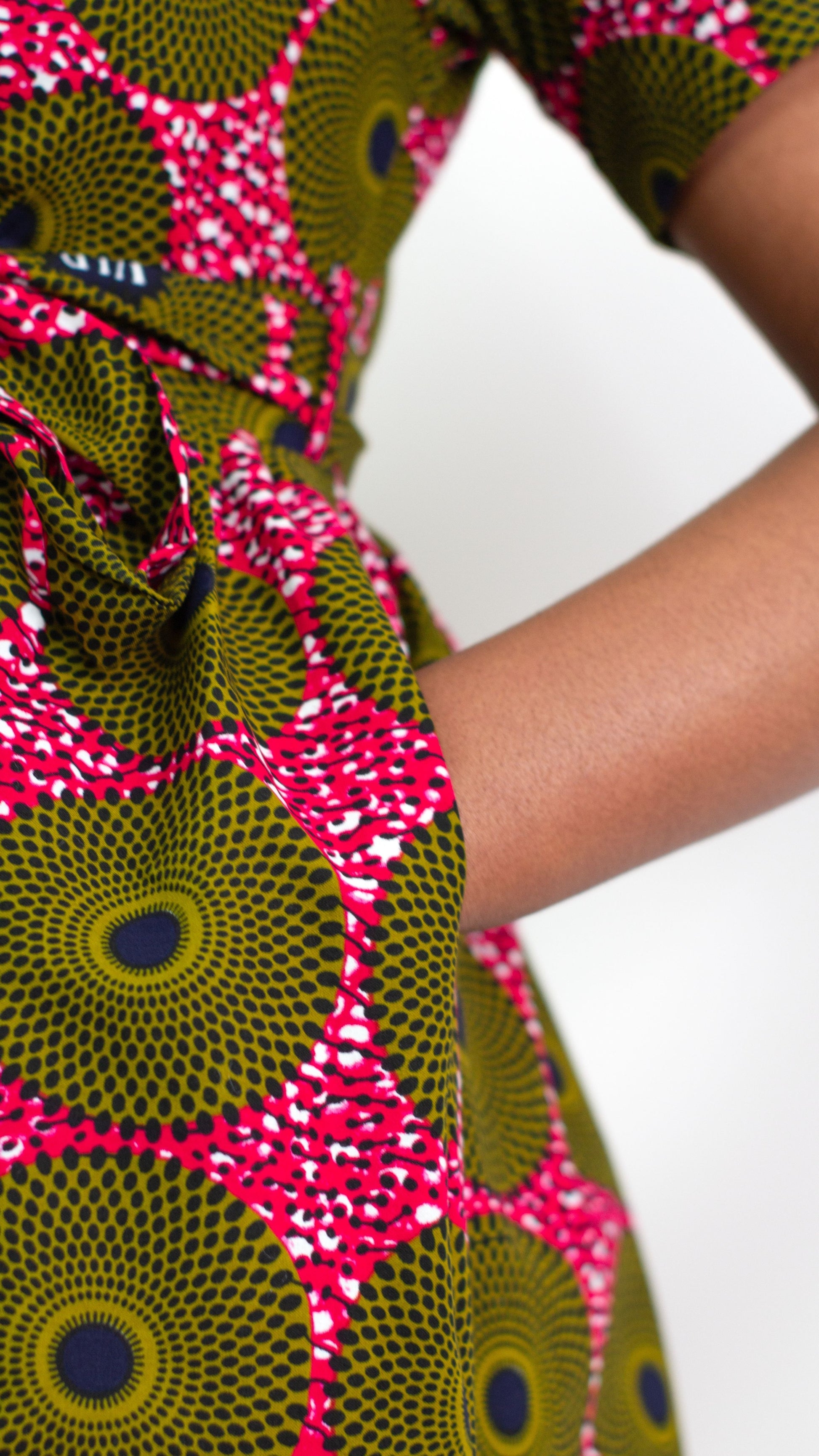 A close-up focusing on a hand in the pocket of the 'Ripple Effect' print on the wrap dress, accentuating both the comfort and practicality of the garment. 