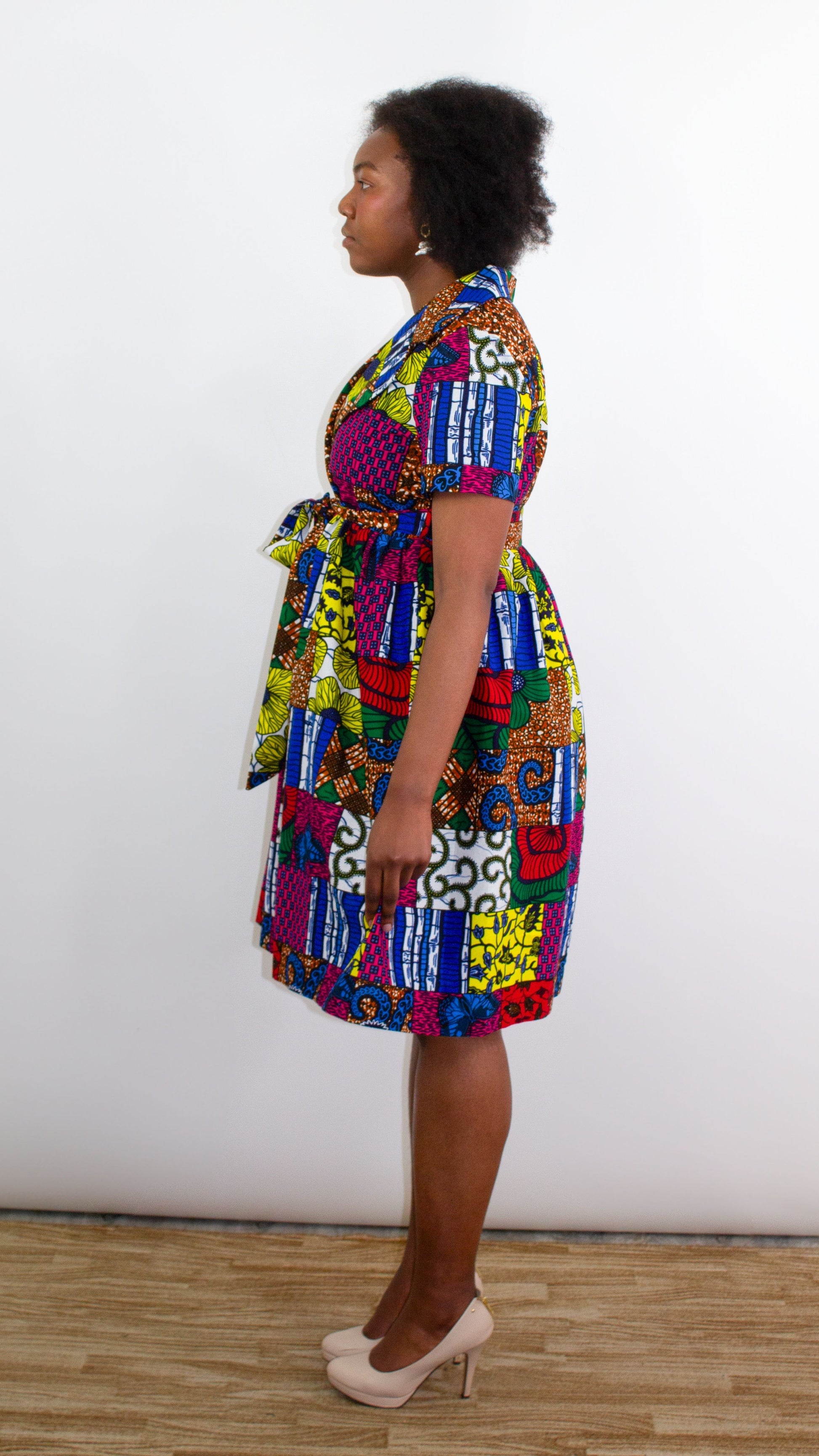 A side view offering a detailed look at a beautiful patchwork dress, highlighting the captivating and colorful print tie belt adorned on the dress. The intricate patchwork design adds a touch of uniqueness and vibrancy.