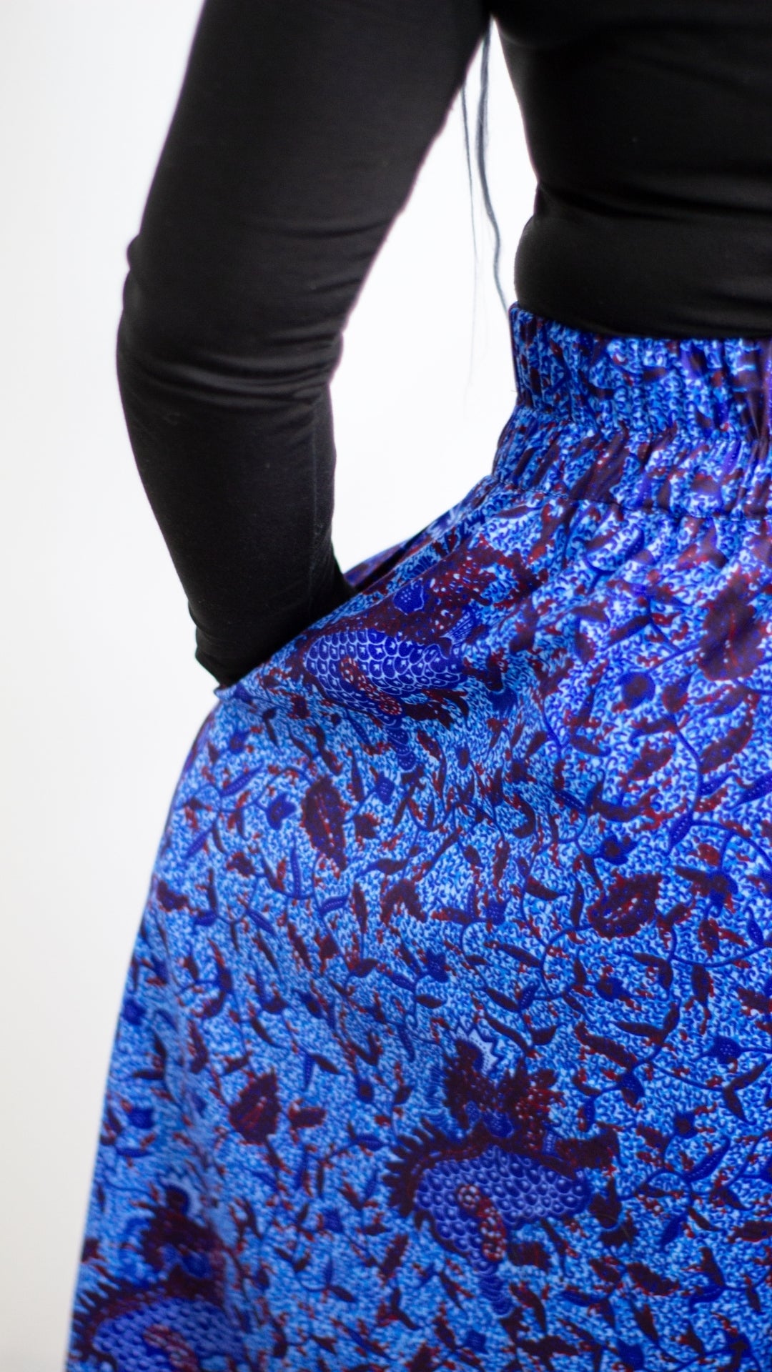 Model's hand placed in the deep hidden pocket of the botanical blue print skirt.
