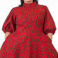 A close up of model in a short red print puff sleeve dress, having placed her hands in pockets.