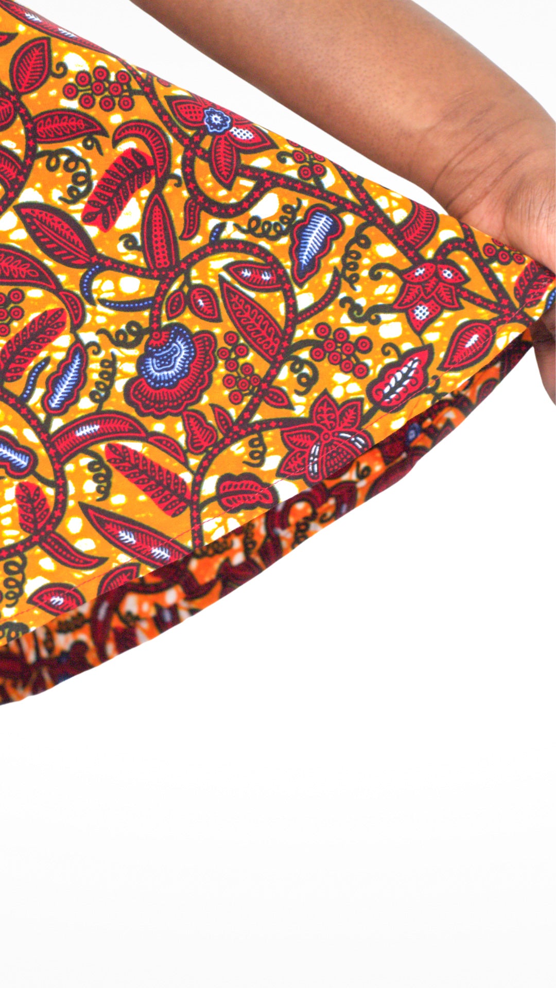 A close up of the red floral elements of the orange print dress showing the high quality of the fabric.