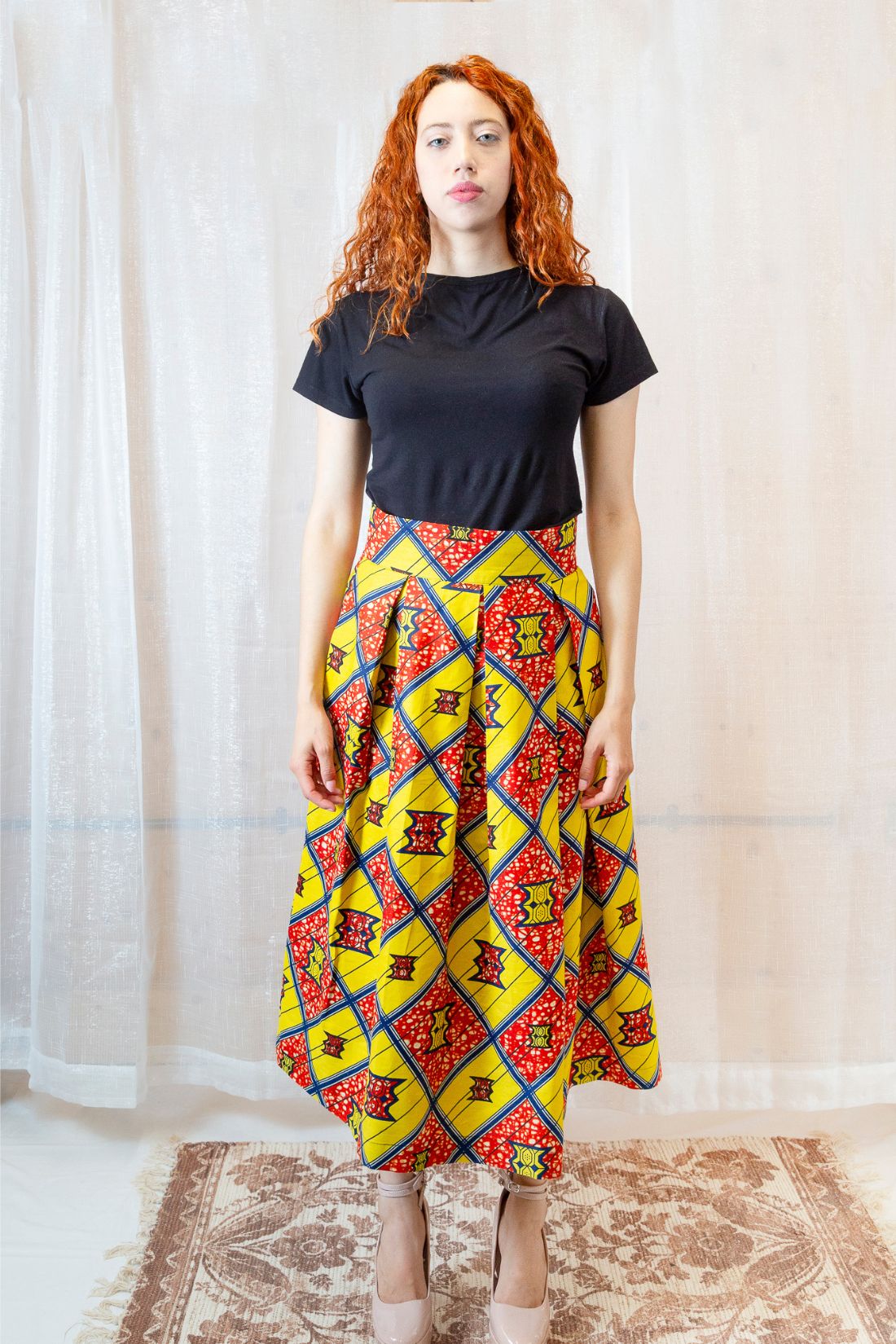 A person wearing an African print yellow and orange skirt